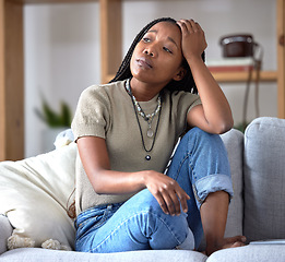 Image showing Black woman, sofa and stress with worry, thinking and sad in home living room with fear of future. African woman, sitting and lounge couch with anxiety, depression or mental health problem in Chicago