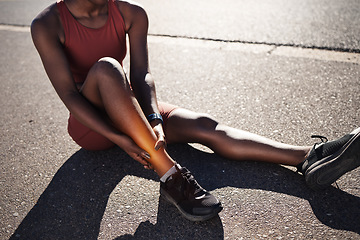 Image showing Leg, injury and pain with a sports black woman holding her ankle outdoor during a fitness workout from above. Ankle, sprain or exercise with a female runner or athlete suffering from an injured joint