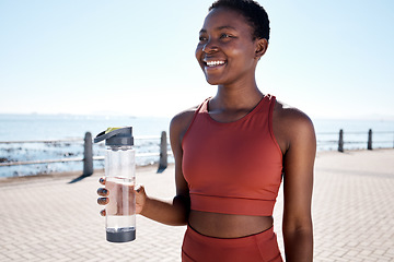 Image showing Fitness, water and black woman runner at beach for training, wellness and cardio by ocean, smile and happy. Exercise, drinking water and woman relax after running, workout and walk with hydration