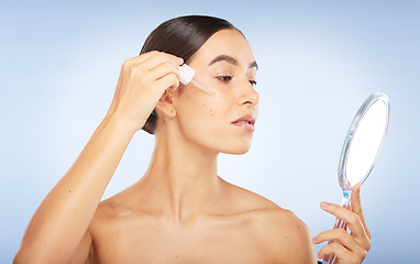 Image showing Face, skincare serum and woman with mirror in studio on a blue background. Beauty, cosmetics and female model with hyaluronic acid, essential oil and dropper product for healthy skin or anti aging.