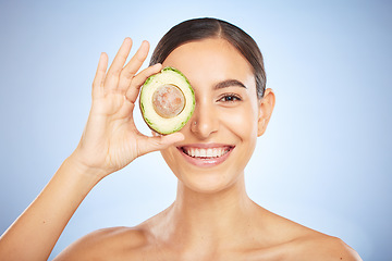 Image showing Face portrait, skincare and woman with avocado isolated on a blue studio background. Beauty, cosmetics and young female model with fruit, food or product for nutrition, healthy fats and vitamin c.