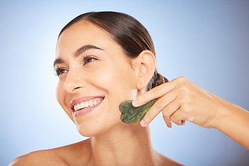 Image showing Skincare, beauty and woman with gua sha in studio on blue background for wellness, healthy skin and glow. Dermatology, spa aesthetic and girl with stone for facial treatment, cosmetics and exfoliate