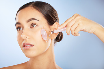 Image showing Woman, face or rose quartz roller for skincare grooming on blue background gradient for collagen treatment, wrinkles or lymph fluid wellness. Zoom, glowing or beauty model with facial stone massage