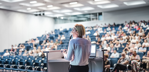 Image showing Female speaker giving a talk on corporate business conference. Unrecognizable people in audience at conference hall. Business and Entrepreneurship event.