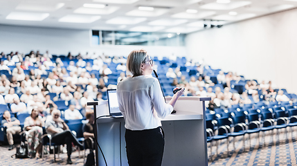 Image showing Female speaker giving a talk on corporate business conference. Unrecognizable people in audience at conference hall. Business and Entrepreneurship event.