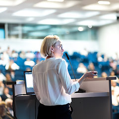 Image showing Female speaker giving a talk on corporate business conference. Unrecognizable people in audience at conference hall. Business and Entrepreneurship event.