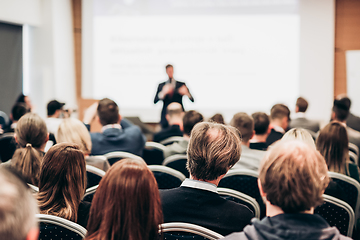 Image showing Speaker giving a talk in conference hall at business event. Rear view of unrecognizable people in audience at the conference hall. Business and entrepreneurship concept.