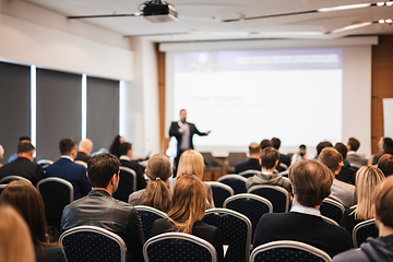 Image showing Speaker giving a talk in conference hall at business event. Rear view of unrecognizable people in audience at the conference hall. Business and entrepreneurship concept.