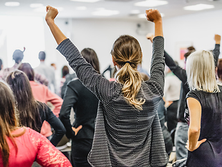 Image showing Participants of interactive motivational speech feeling empowered and motivated, hands raised high in the air.