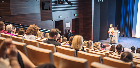 Image showing Speaker giving a talk in conference hall at business event. Rear view of unrecognizable people in audience at the conference hall. Business and entrepreneurship concept.