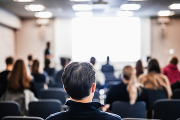 Image showing Speaker giving a talk in conference hall at business event. Rear view of unrecognizable people in audience at the conference hall. Business and entrepreneurship concept.