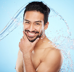 Image showing Portrait, water and shower with a man model in studio on a blue background for hygiene or hydration. Face, beauty and skincare with a handsome young male wet from a water splash in the bathroom