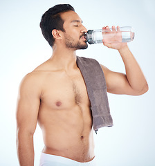 Image showing Fitness, health or man drinking water in studio after training in workout or exercise for body goals or wellness. Motivation, weight loss or tired healthy person relaxing and drinks liquid or bottle