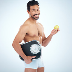 Image showing Portrait, fitness and man with apple and scale in studio isolated on a blue mockup background. Weight loss, healthy diet and happy male model with fruit or food for nutrition, vitamin c and wellness.