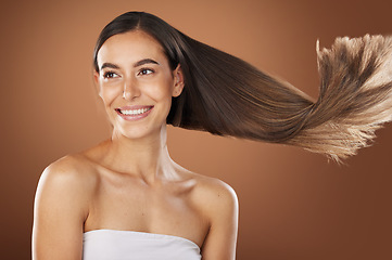 Image showing Hair, beauty and skincare with a model woman in studio on a brown background for natural or keratin treatment. Face, haircare and salon with an attractive young female posing to promote a product