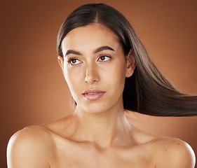 Image showing Hair, beauty and skincare with a model woman in studio on a brown background for natural or keratin treatment. Face, haircare and salon with an attractive young female posing to promote a product