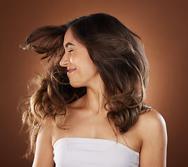 Image showing Hair, beauty and skincare with a model woman in studio on a brown background for natural or keratin treatment. Face, haircare and salon with an attractive young female posing to promote a product