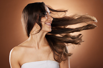 Image showing Hair, beauty and skincare with a model woman in studio on a brown background for natural or keratin treatment. Face, haircare and salon with an attractive young female posing to promote a product