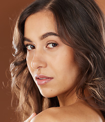 Image showing Woman, face skincare or curly hairstyle on brown studio background in color dye advertising, self love or Brazilian keratin treatment. Portrait, beauty model or brunette waves and natural makeup glow