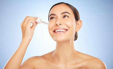 Image showing Face, skincare and beauty of woman with serum in studio on a blue background. Thinking, cosmetics or aesthetics of female model with hyaluronic acid, dropper product or essential oil for healthy skin