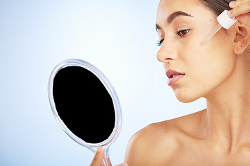 Image showing Face, skincare serum and woman with mirror in studio on a blue background. Beauty, cosmetics and female model with hyaluronic acid, essential oil and dropper product for healthy skin or anti aging.