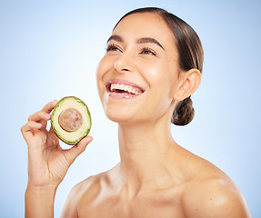 Image showing Woman, face or skincare glow with avocado on blue background in studio healthcare wellness, grooming routine or organic food dermatology. Smile, happy or beauty model with diet fruit for relax facial