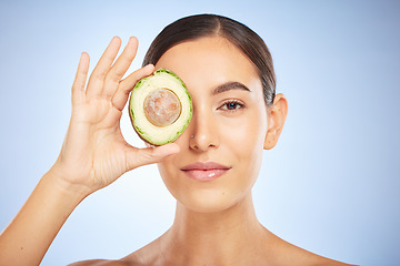 Image showing Face portrait, skincare and woman with avocado isolated on a blue studio background. Beauty, cosmetics and young female model with fruit, food or product for nutrition, healthy fats and vitamin c.