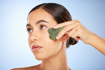 Image showing Skincare, beauty and woman with gua sha in studio on blue background for wellness, healthy skin and glow. Dermatology, spa aesthetic and girl with stone for facial treatment, cosmetics and exfoliate