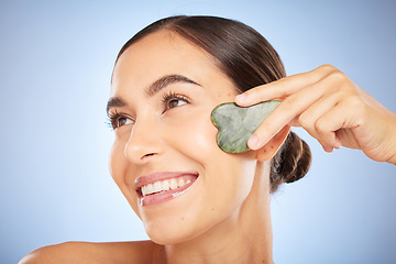 Image showing Skincare, beauty and woman with gua sha in studio on blue background for wellness, healthy skin and glow. Dermatology, spa aesthetic and girl with stone for facial treatment, cosmetics and exfoliate