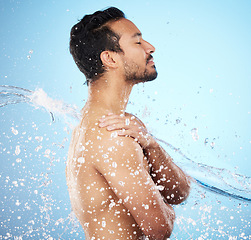 Image showing Man, water splash and clean for skincare, wellness and health with beauty, grooming and on blue studio background. Cleaning, male and shower for washing, organic care and hygiene for natural skin.