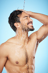 Image showing Face, water splash and man in shower cleaning for body care in studio isolated on a blue background. Hygiene, skincare and profile of male model bathing and washing for health, wellness and beauty.