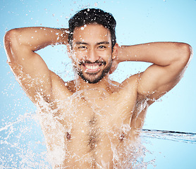 Image showing Portrait, water and shower with a man model in studio on a blue background for hygiene or hydration. Face, beauty and skincare with a handsome young male wet from a water splash in the bathroom