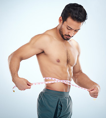 Image showing Man, body or measuring tape on waist on studio background for weight loss management, fat control or bmi and diet wellness. Fitness model, sports athlete or coach with tape measure for muscle goals