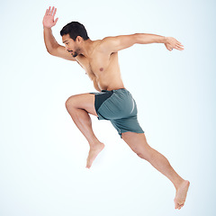 Image showing Running, jump and fitness of man in studio isolated on a blue background mock up. Sports, training and male model, athlete or runner jumping, sprint workout and exercising for health and wellness.