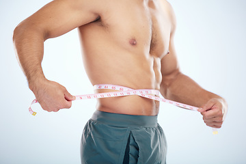 Image showing Man, body or measuring tape on waist on studio background for weight loss management, fat control or bmi and diet wellness. Fitness model, sports athlete or coach with tape measure for muscle goals