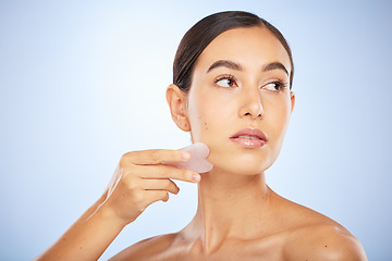 Image showing Woman, face and gua sha product for skincare wellness, beauty or healthy skin glow in blue background studio. Model, facial care and salon spa therapy with stone tool for natural dermatology detox