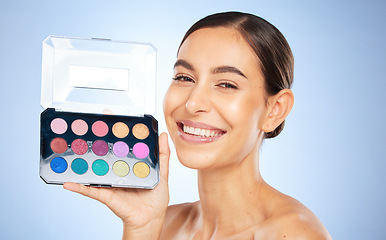 Image showing Beauty, makeup and eye shadow pallet with a model woman in studio on a blue background to apply color. Portrait, face and cosmetics with an attractive young female posing to promote a skin product