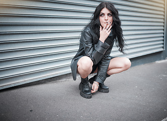 Image showing Punk, emo and woman smoking a cigarette in the street of an urban city in Canada in an edgy black outfit. Grunge, rocker and girl smoker with tobacco to smoke while sitting in the road in town.