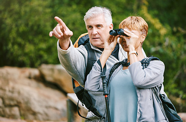 Image showing Elderly, couple hiking and fitness, adventure outdoor with hike together, active lifestyle with freedom and travel. Nature, trekking and senior man pointing and woman with binocular for bird watching