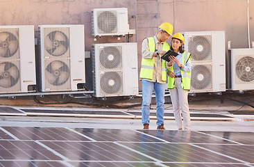 Image showing Tablet, solar energy or engineering team on roof in a city planning, talking or speaking of renewable energy. Solar panels, collaboration or electricians working on photovoltaic development project