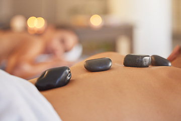 Image showing Stone, man or woman at a spa for a massage, relaxing self care or luxury physical therapy healing for back pain. Hot stone massage, zoom or customer on a bed for healthy natural holistic treatment