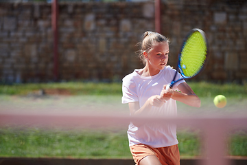 Image showing A young girl showing professional tennis skills in a competitive match on a sunny day, surrounded by the modern aesthetics of a tennis court.