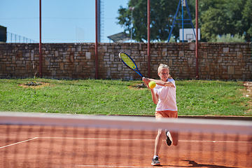 Image showing A young girl showing professional tennis skills in a competitive match on a sunny day, surrounded by the modern aesthetics of a tennis court.