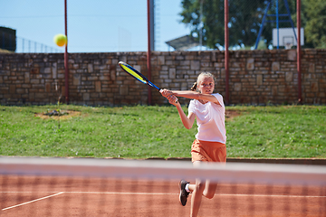 Image showing A young girl showing professional tennis skills in a competitive match on a sunny day, surrounded by the modern aesthetics of a tennis court.