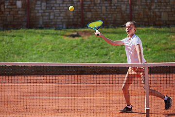 Image showing A young girl showing professional tennis skills in a competitive match on a sunny day, surrounded by the modern aesthetics of a tennis court.