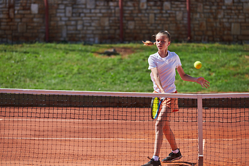 Image showing A young girl showing professional tennis skills in a competitive match on a sunny day, surrounded by the modern aesthetics of a tennis court.