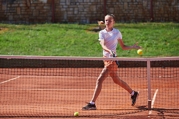 Image showing A young girl showing professional tennis skills in a competitive match on a sunny day, surrounded by the modern aesthetics of a tennis court.