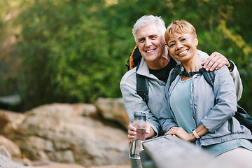 Image showing Nature, hiking and portrait of a senior couple relaxing while walking in a forest for exercise. Love, happy and elderly people with a smile sitting to rest while trekking together in the woods.