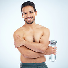 Image showing Man, fitness and water bottle in studio portrait with smile, health or wellness exercise by blue background. Model, shirtless or water for self care, self love or body positivity by studio backdrop