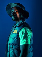 Image showing Fashion, trendy and black man model in a studio with a cool, stylish and casual outfit with lighting. Edgy, style and modern fashionable African male posing while isolated by a blue background.